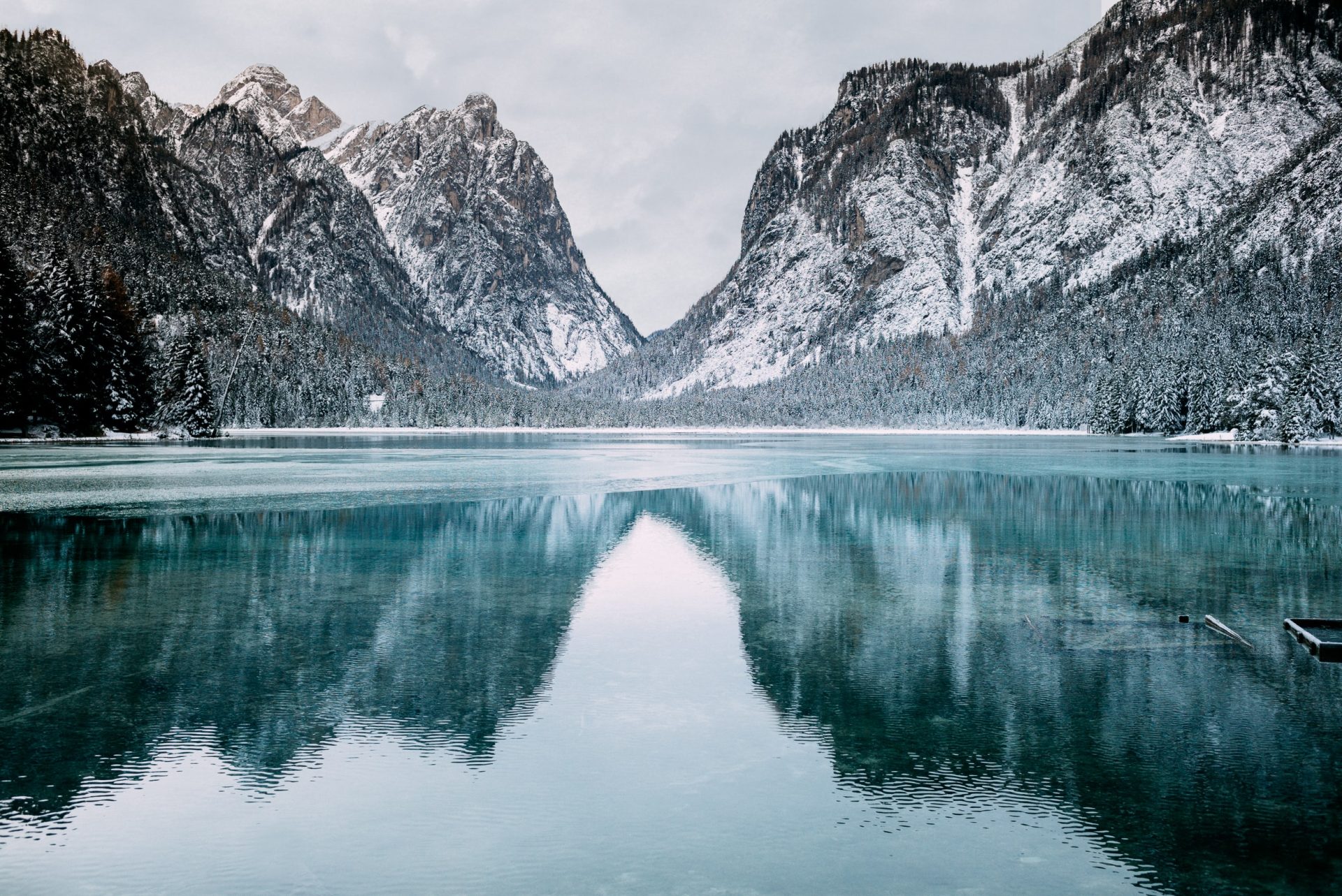 snow topped cliffs and trees surrounding a crystal blue lake